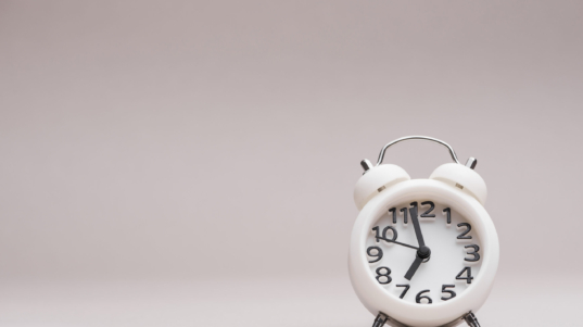 white-miniature-alarm-clock-against-colored-backdrop